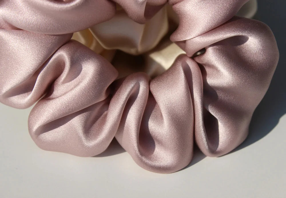 A close-up of pink silk hair scrunchies gathered in a circular arrangement.