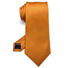Cravate de soie jacquard orange uni roulée et présentée sur fond blanc.