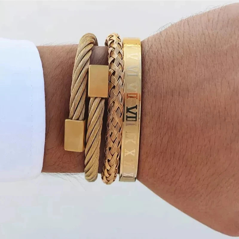 A gold stainless steel bracelet featuring Roman numerals and a braided cord, worn on a wrist.