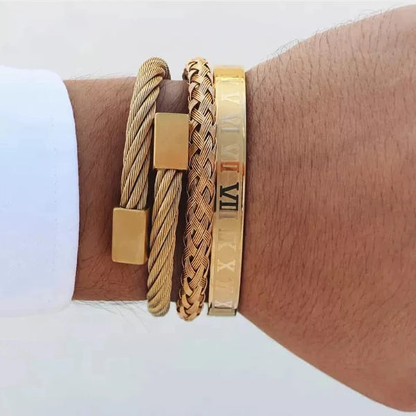A gold stainless steel bracelet featuring Roman numerals and a braided cord, worn on a wrist.
