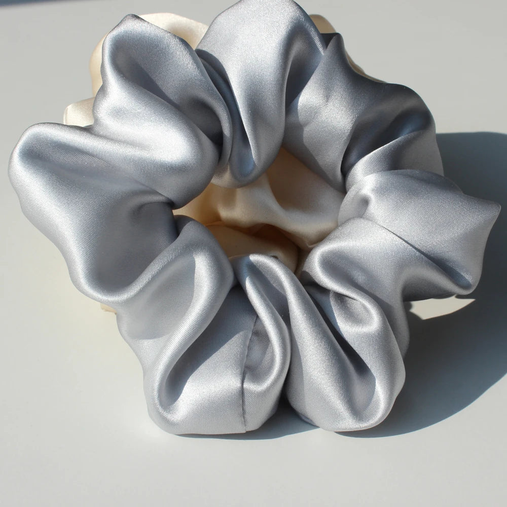 A cluster of silky gray hair scrunchies gathered in a rosette shape on a light background.