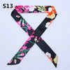 A black silk headband scarf featuring a multi-color floral print with pink, orange, and white flowers.