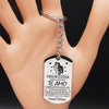 A silver stainless steel love keychain with engraved text in Spanish and English hanging from a bracelet.