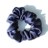 A black satin scrunchie with gathered fabric texture shown against a white background.