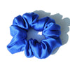 A blue silk hair scrunchie tied in a bow shape, shown against a white background.