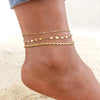 Gold stainless steel anklets worn on a person's ankle.