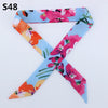 A multi-color silk headband scarf featuring floral patterns in pink, orange, and blue on a diagonal cross design.