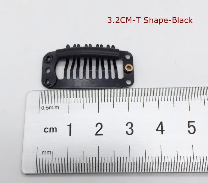 Une pince pour extension de cheveux noire avec un design en forme de T, à côté d'une règle pour l'échelle.