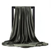 Una bufanda de seda satinada verde oliva oscuro drapeada sobre un soporte negro.
