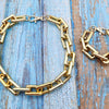 A gold-colored boho punk twisted link chain necklace lying on a weathered blue wooden surface.