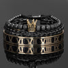 Pila de pulseras de esmalte en números romanos negro y dorado sobre una superficie reflectante.