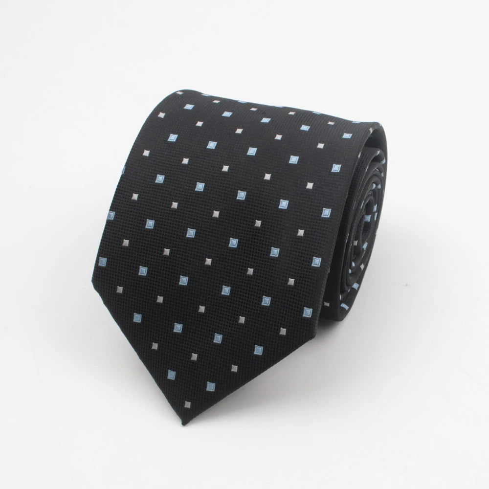 A black necktie with a pattern of small blue dots and stripes rolled up.