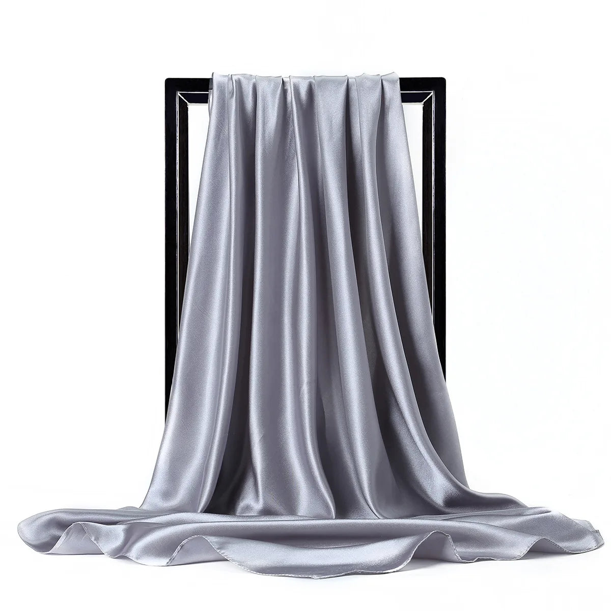 Una bufanda de seda satinada plateada drapeada colgada en un soporte negro.