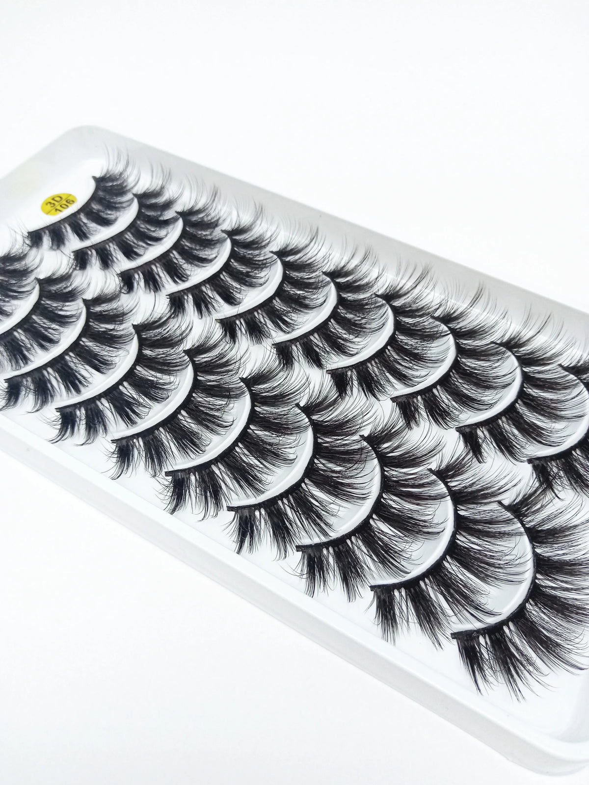 A strip of dramatic mink false eyelashes is displayed on a white plastic tray.