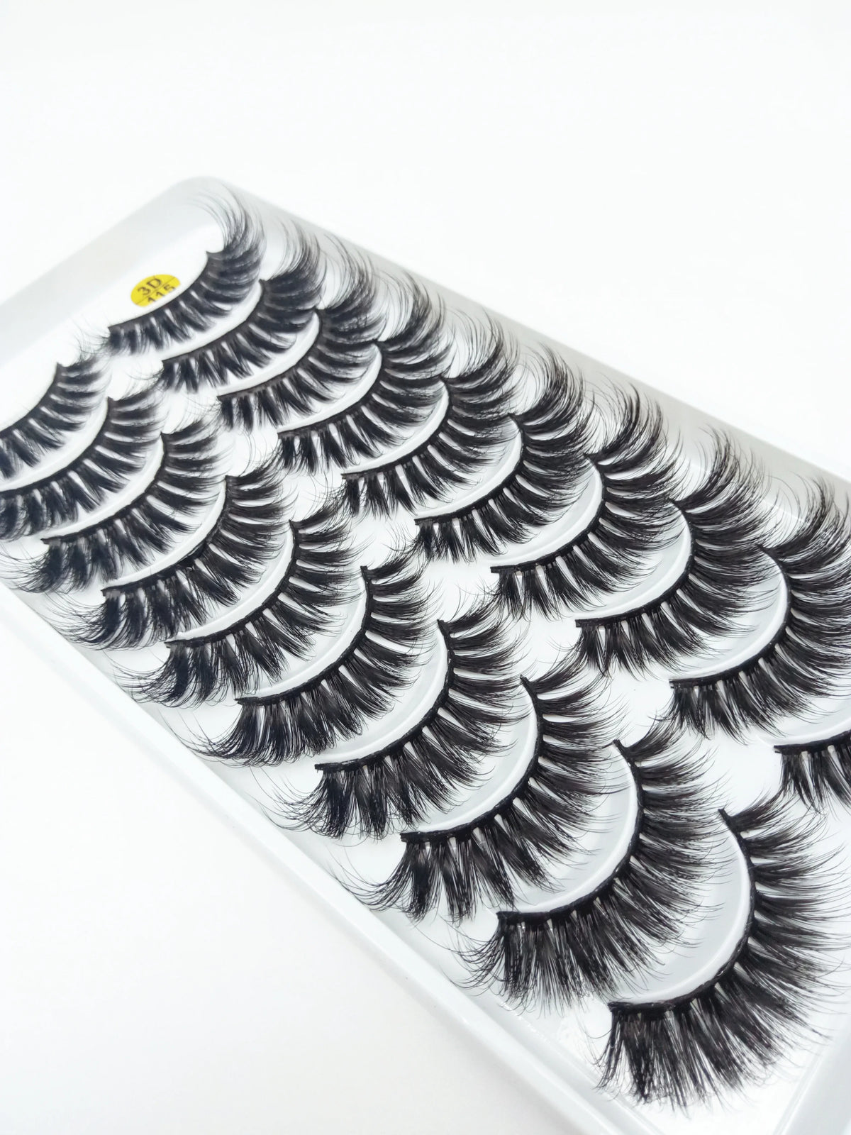 A strip of dramatic mink false eyelashes is shown on a white plastic tray.