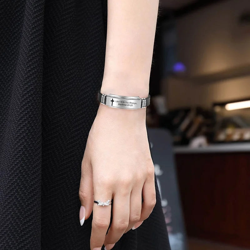 A close-up of a woman's wrist wearing a silver scripture quote bracelet on her hand.
