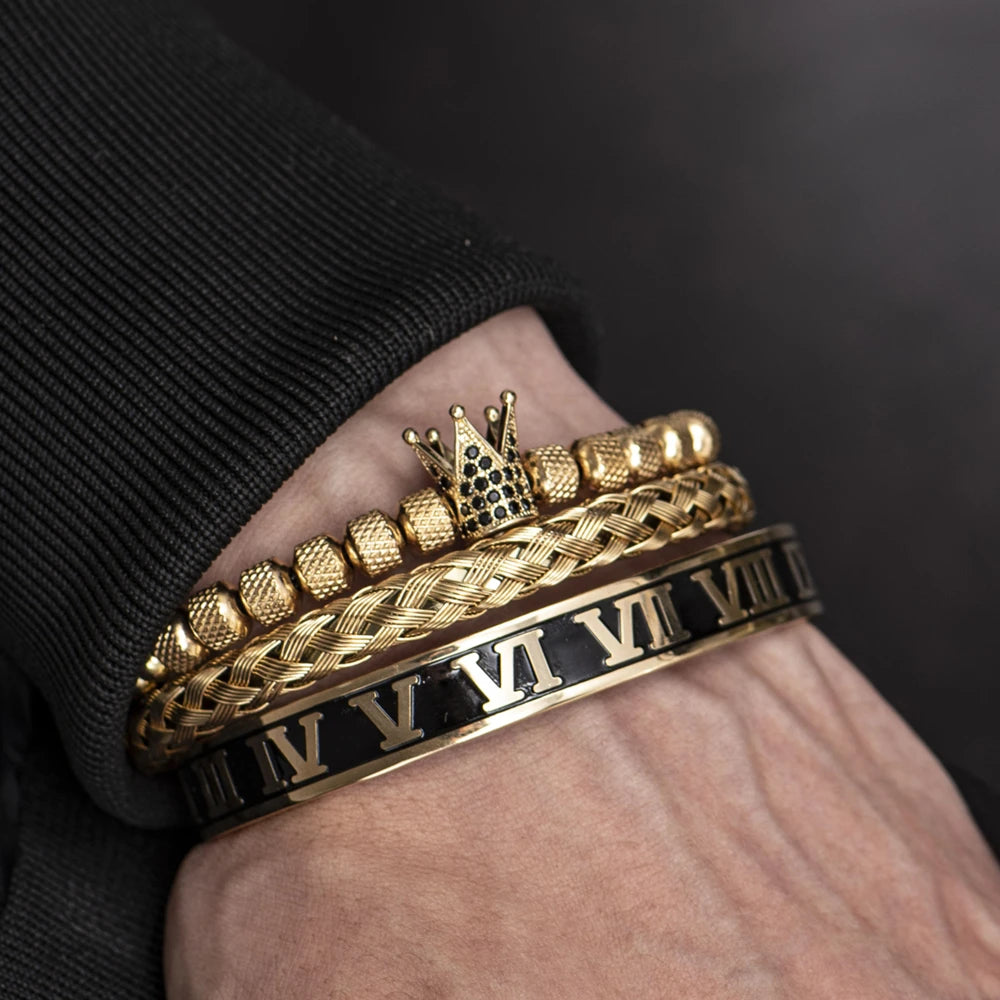 Primer plano de una mano con pulseras apiladas de esmalte dorado y negro con números romanos.