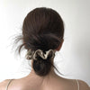 A close-up of a woman's dark hair pulled back into a low bun with silk scrunchies.