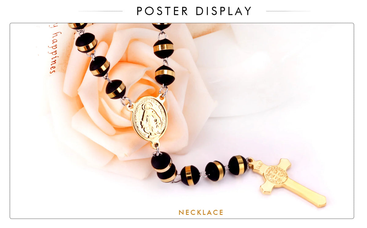 Collar de cruz de Virgen María de acero inoxidable dorado con cuentas negras y cadena extensible, exhibido en una rosa rosa.