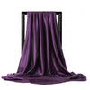 Pañuelo de seda satín morado drapeado colgado en un soporte negro.