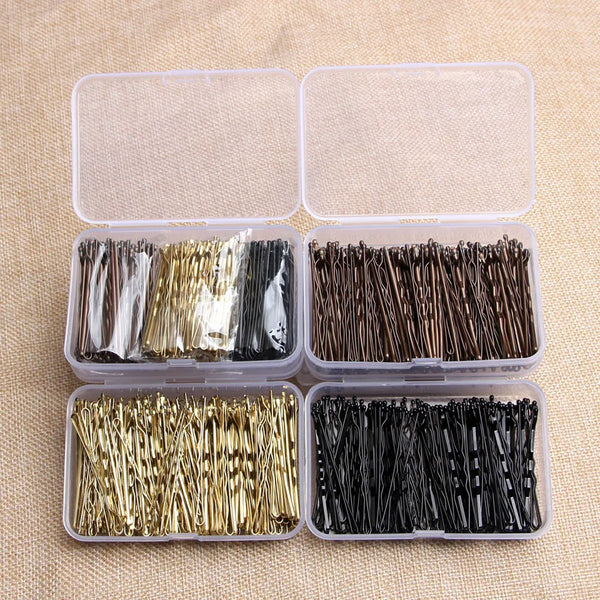 Un juego de elegantes pinzas para el cabello de metal en varios colores y acabados, empaquetadas en recipientes de plástico t