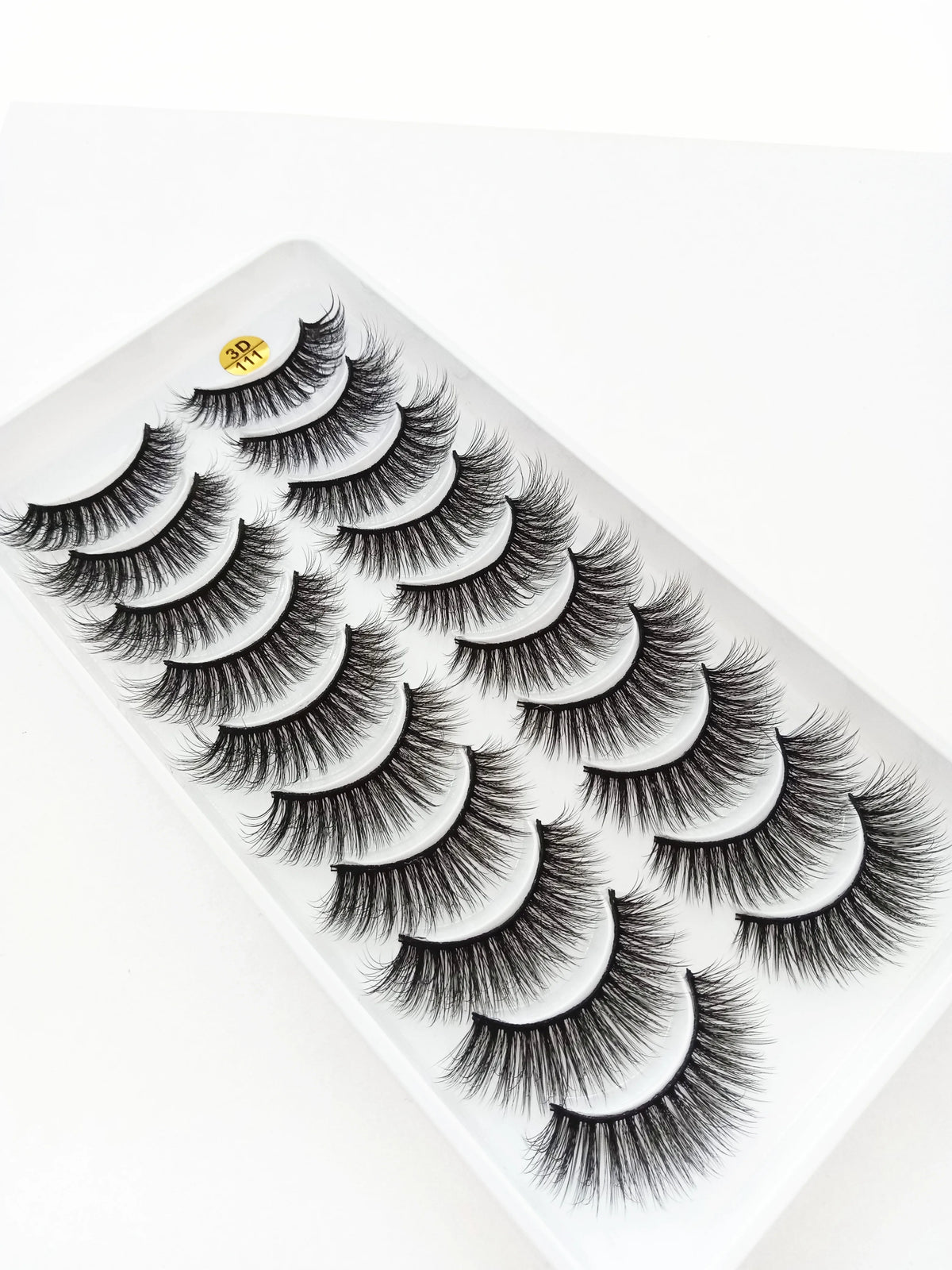 A close-up of dramatic mink false eyelashes applied to a white surface.