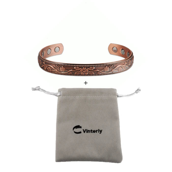 A pure copper magnetic bangle with a plum flower design next to a gray pouch labeled Vinterly.