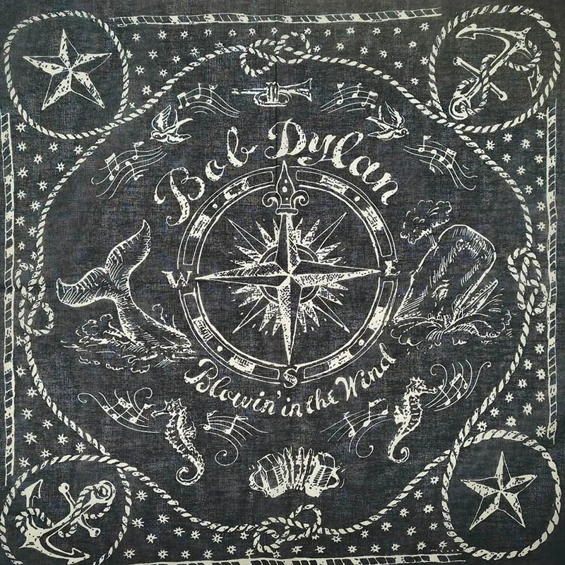 Bandana bordada en blanco y negro con diseño de calavera y tibias cruzadas rodeado de elementos decorativos.