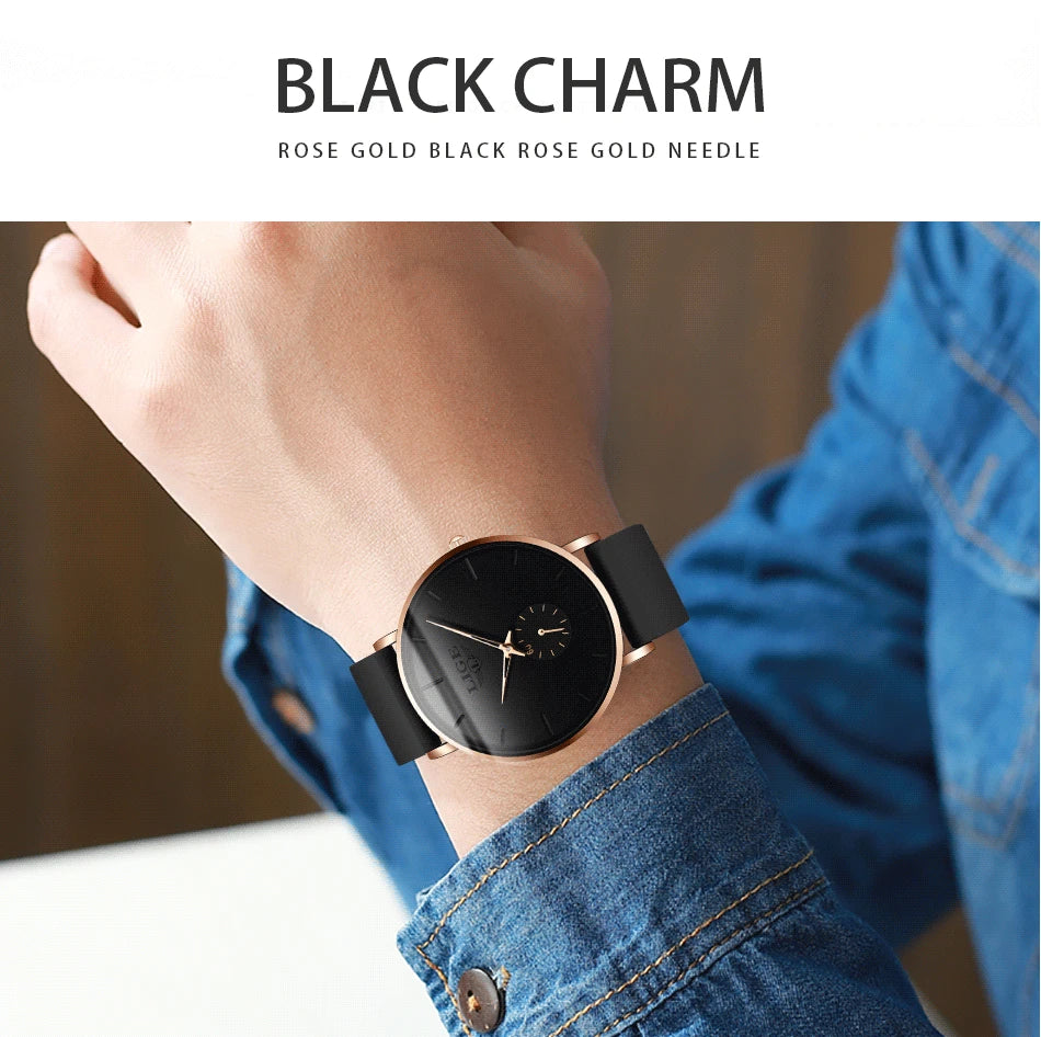 A close-up of a black rose gold needle watch worn on a wrist against a blue denim shirt.