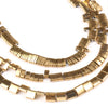 A close-up of gold-plated hematite round cube beads arranged in multiple strands for DIY jewelry making.