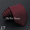 A dark red patterned tie with small dots is shown rolled and draped on a dark background.