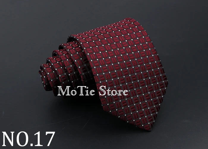 A dark red patterned tie with small dots is shown rolled and draped on a dark background.