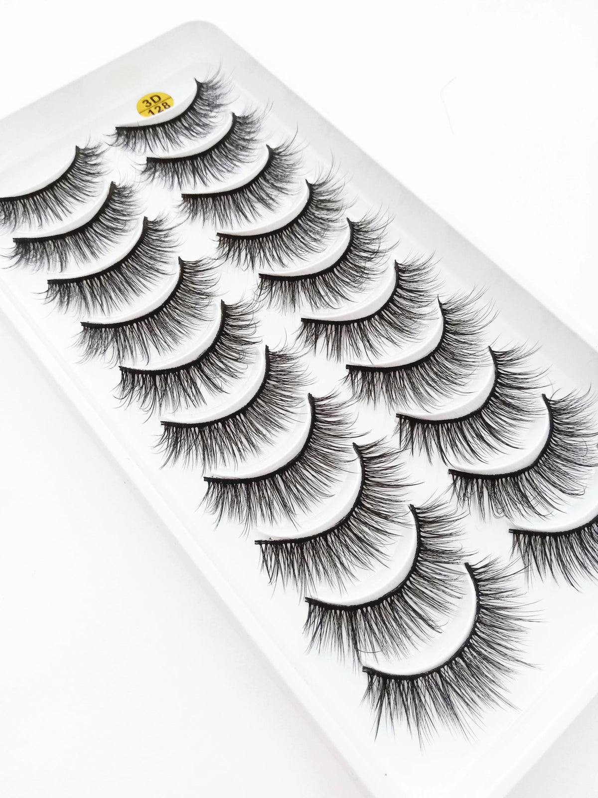 A display of dramatic mink false eyelashes arranged in a fan pattern on a white tray.