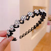 A hand holds a black elastic hair hoop decorated with sparkling clear rhinestones and floral accents.