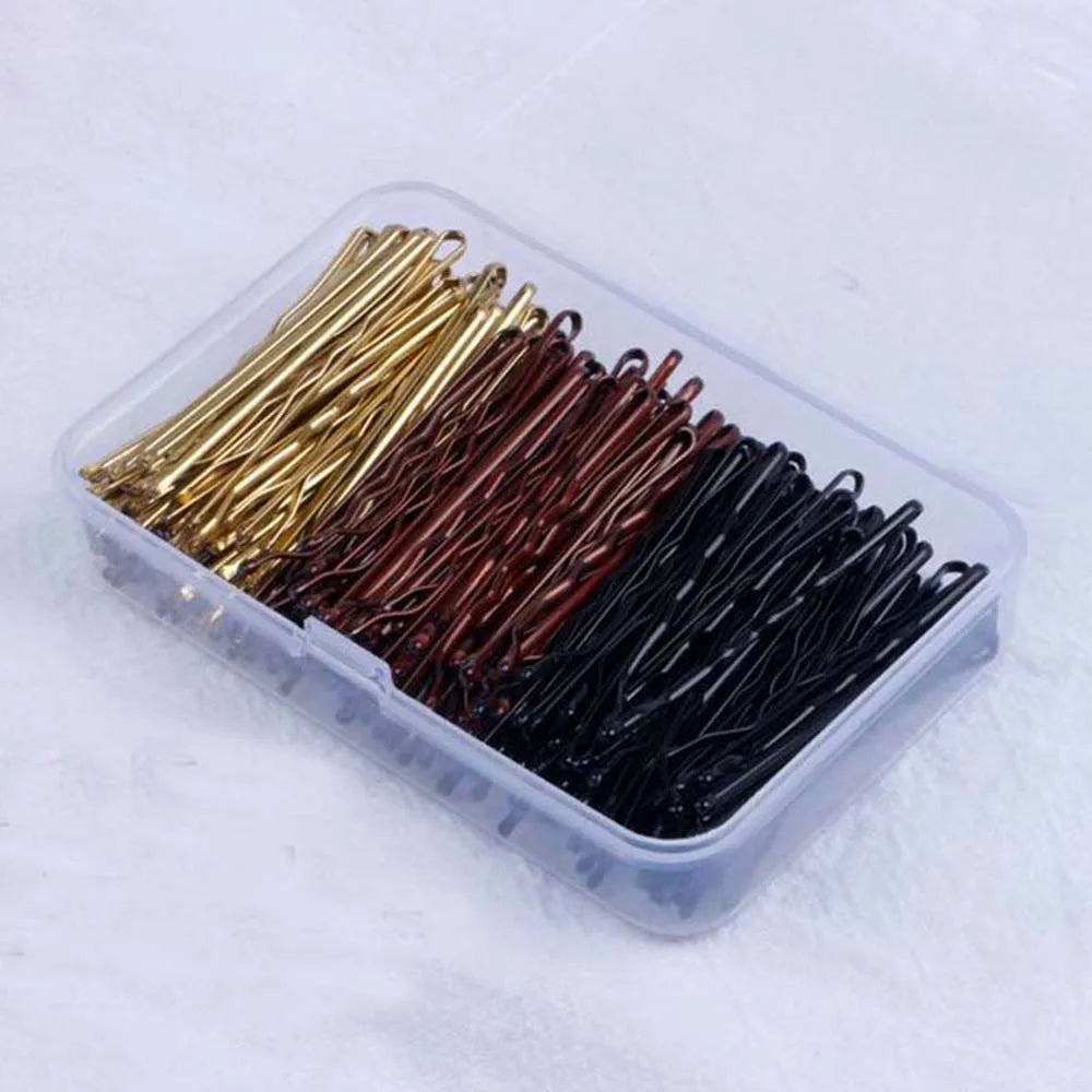 A clear plastic container filled with various colored metal hair clips for styling.