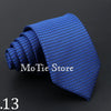 A dark blue knitted tie rolled into a spiral shape, shown against a black background.