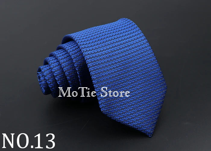 A dark blue knitted tie rolled into a spiral shape, shown against a black background.