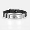 A black leather bracelet with a silver plate engraved with the text Love Never Fails 1 Cor 13:8