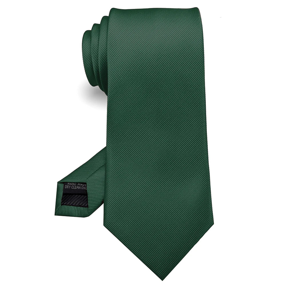 Cravate en soie jacquard vert foncé roulée et présentée sur fond blanc.