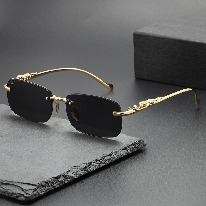 Gold-rimmed, black square sunglasses resting on a dark gray surface.