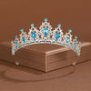 An elegant crystal baroque bridal tiara headpiece featuring blue gemstones and clear crystals displayed on a box.