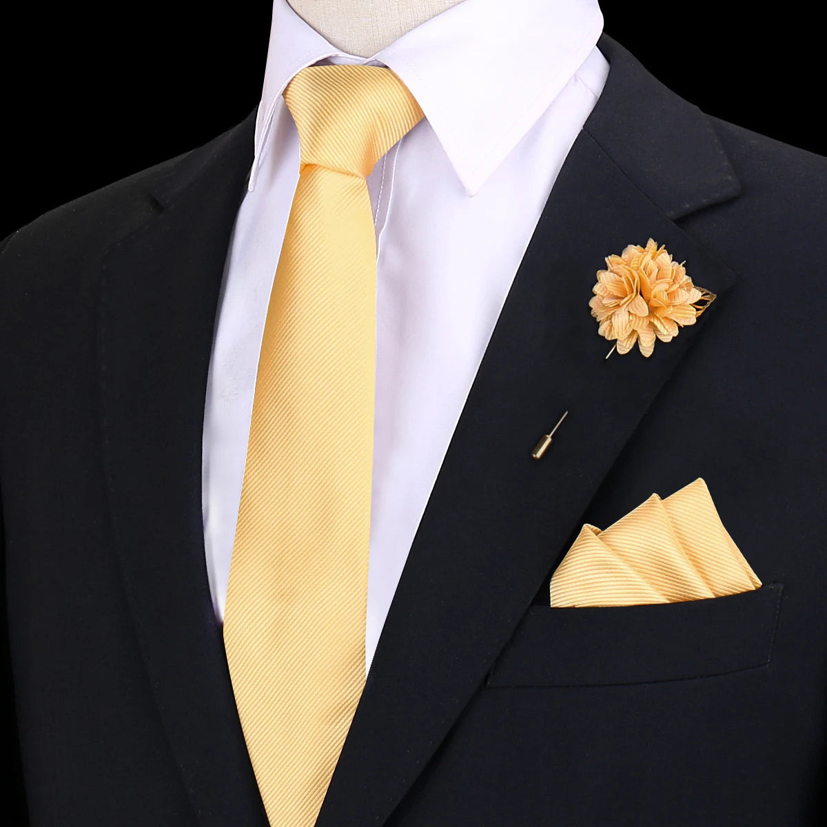 Chaqueta negra, camisa blanca, corbata de seda amarilla a rayas y flor de tela dorada.