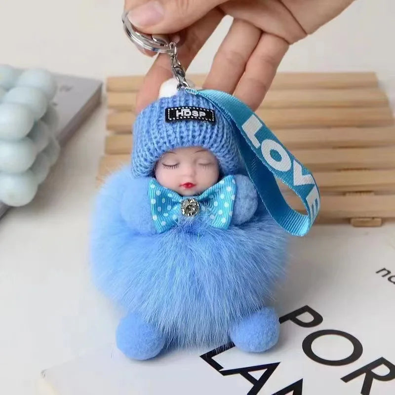 A cute blue fluffy plush doll with a knitted hat and bow, attached to a silver keychain.