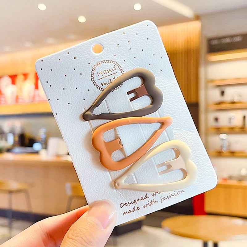 A set of vintage frosted geometry hair clips in various shades of beige and gray displayed on a white card.