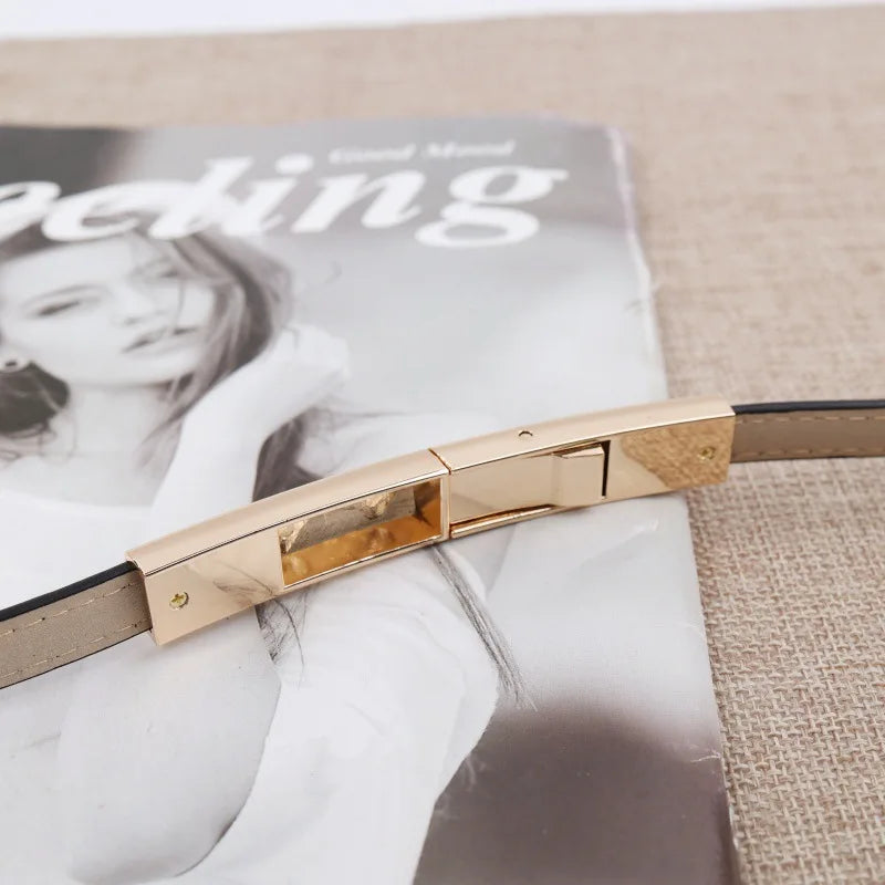 Nahaufnahme eines eleganten, schlanken Pendlergurts mit goldener Schnalle auf einer Magazinseite.