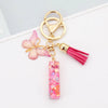 Gold acrylic letter keychain with a pink butterfly charm and a magenta tassel
