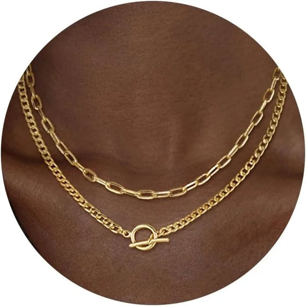 Gold layered Cuban link necklace displayed on a brown fabric background.