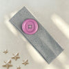 A pink vintage polka dot button headband resting on a light surface with silver glitter stars.