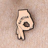 A gold-toned enamel pin shaped like a hand making a peace sign with the word GOTCHA inscribed on the palm.