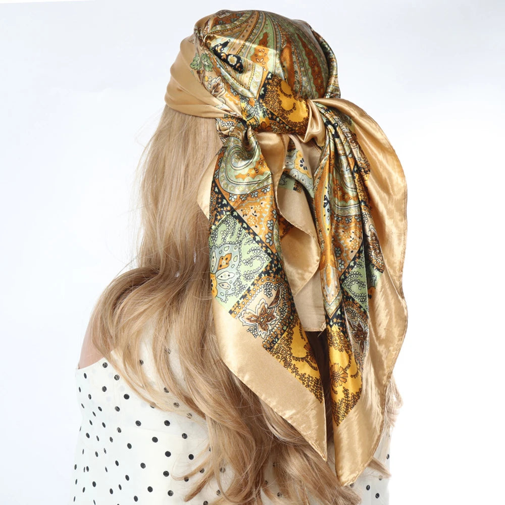 Langes blondes Haar einer Frau, gestylt mit einem Seiderschal mit aufwendigem Muster in Gold- und Olivtönen.